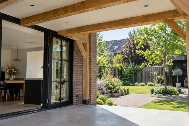 Moderne aanbouw met openslaande deuren en houten balken, met uitzicht op een bloeiende tuin