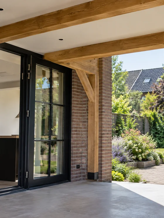 Moderne aanbouw met openslaande deuren en houten balken, met uitzicht op een bloeiende tuin