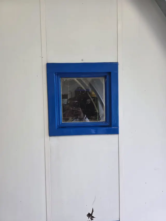 Wit gelakte houten gevelbekleding met een blauw gelakt raamkozijn
